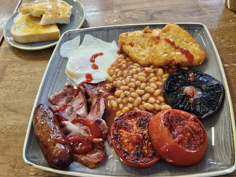 Full English breakfast with sausages, bacon, fried egg, beans, hash browns, tomato and mushroom
